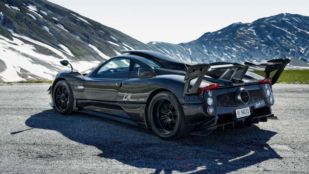 Sleek Black Sports Car Powerhouse on Snowy Mountain Road wallpaper