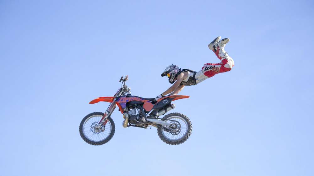 Daring Motocross Stunt in the Clear Blue Sky wallpaper