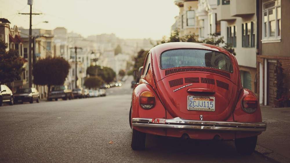 Vintage Red Beetle Cruising Through the Streets wallpaper