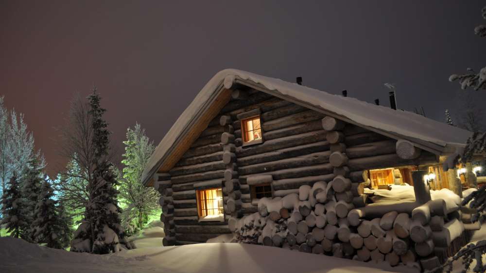 Snowy log cabin at night wallpaper
