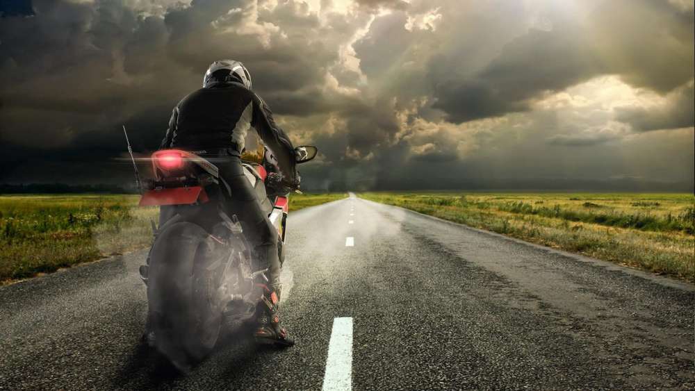 Motorcyclist's Journey Under Approaching Storm wallpaper