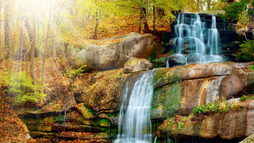 Sunlit Waterfall in a Forest Sanctuary wallpaper