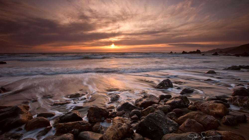 Serene Sunset Over Rocky Shoreline wallpaper