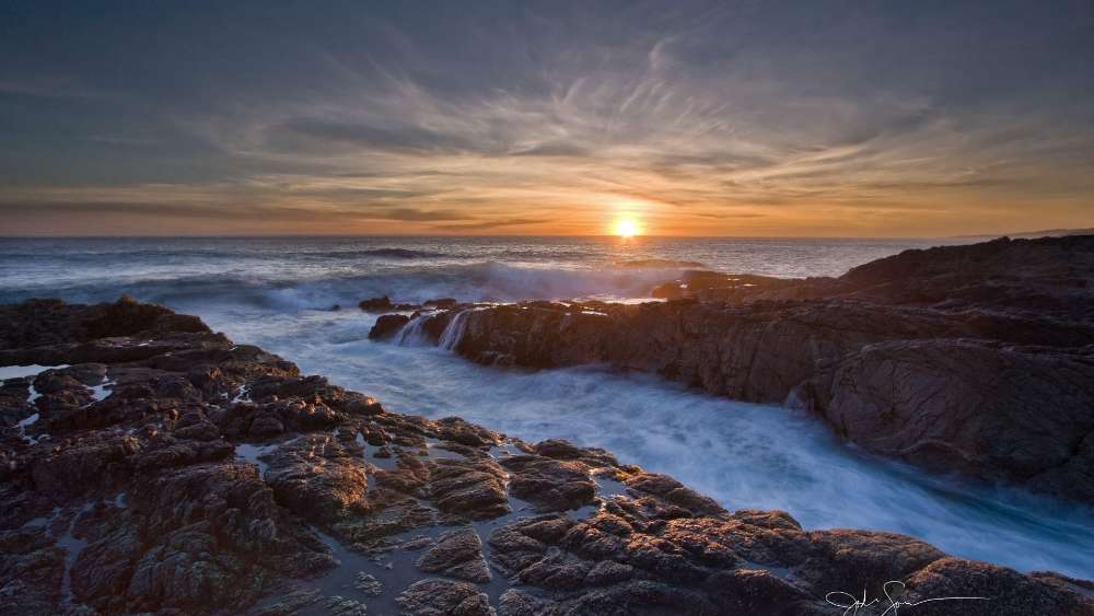 Majestic Sunset Over Rocky Shoreline wallpaper