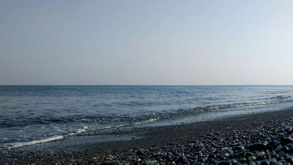 Calm Seascape with Smooth Pebbles and Clear Sky wallpaper