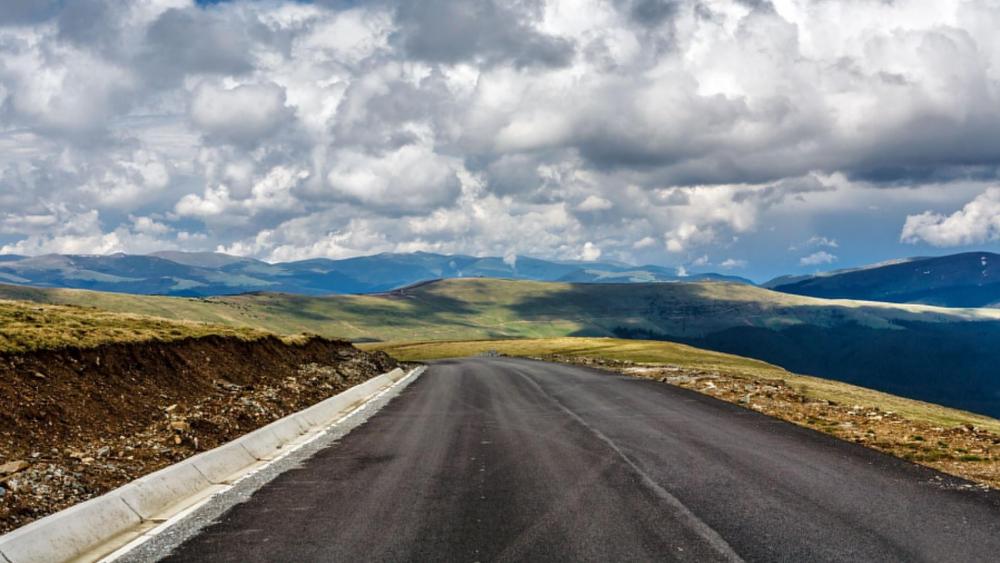 Cloudy sky above the endless road wallpaper