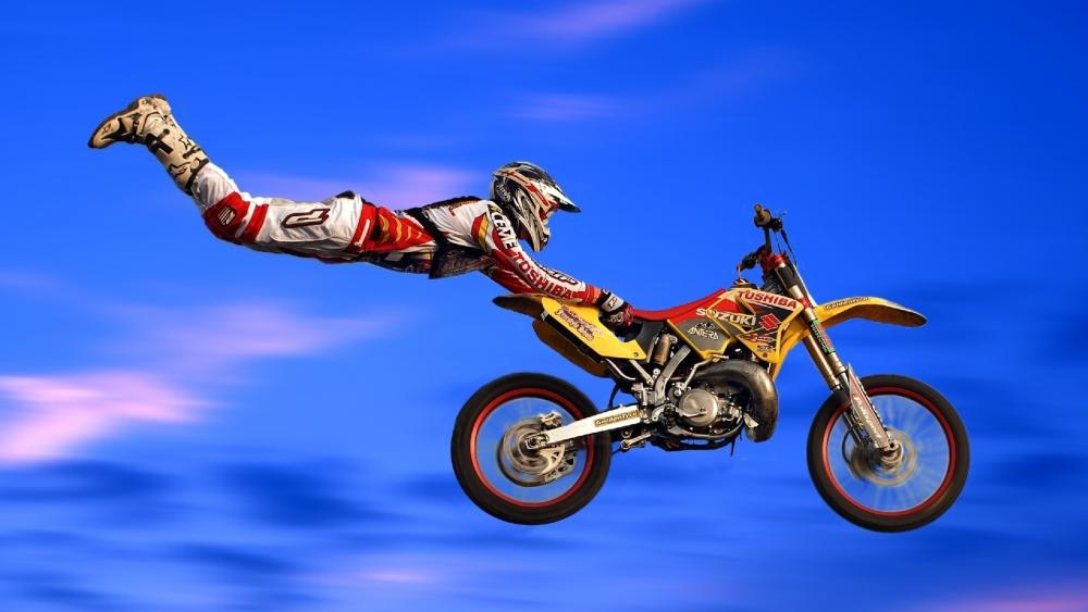 Daring Motocross Stunt Against Blue Sky wallpaper