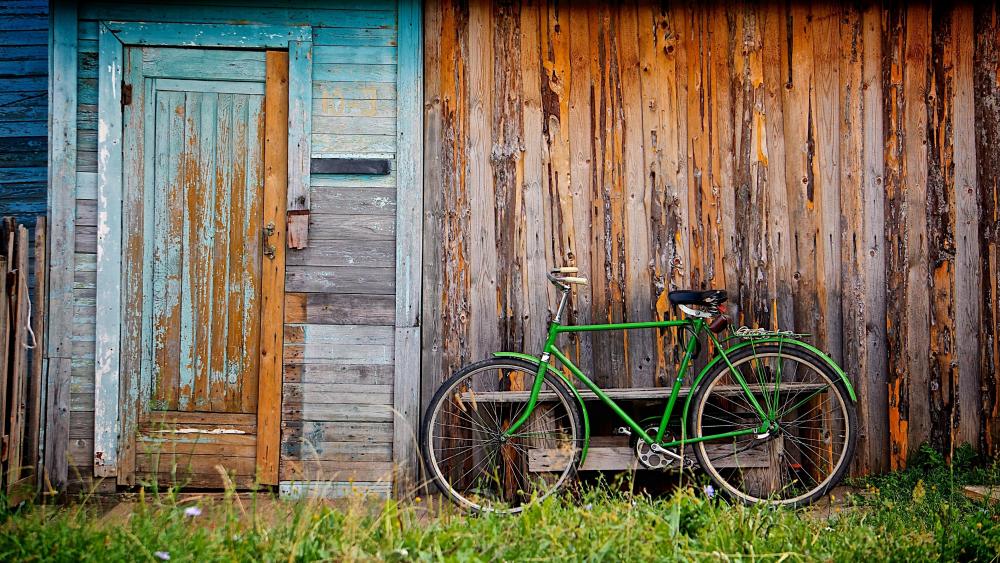A green bicycle in front of a cabin wallpaper