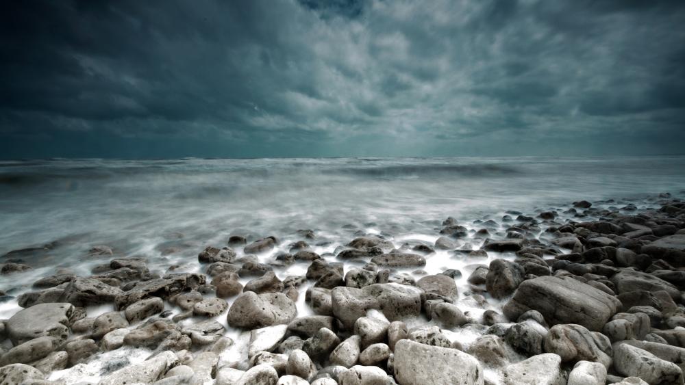 Stormy clouds above the stony beach wallpaper