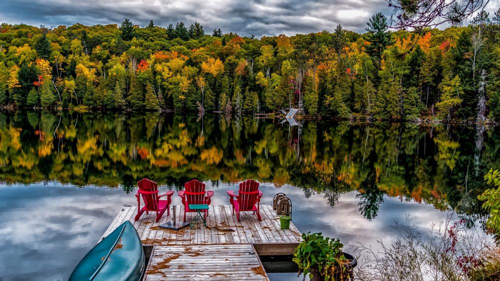 Jetty with seats on a calm lake at fall wallpaper