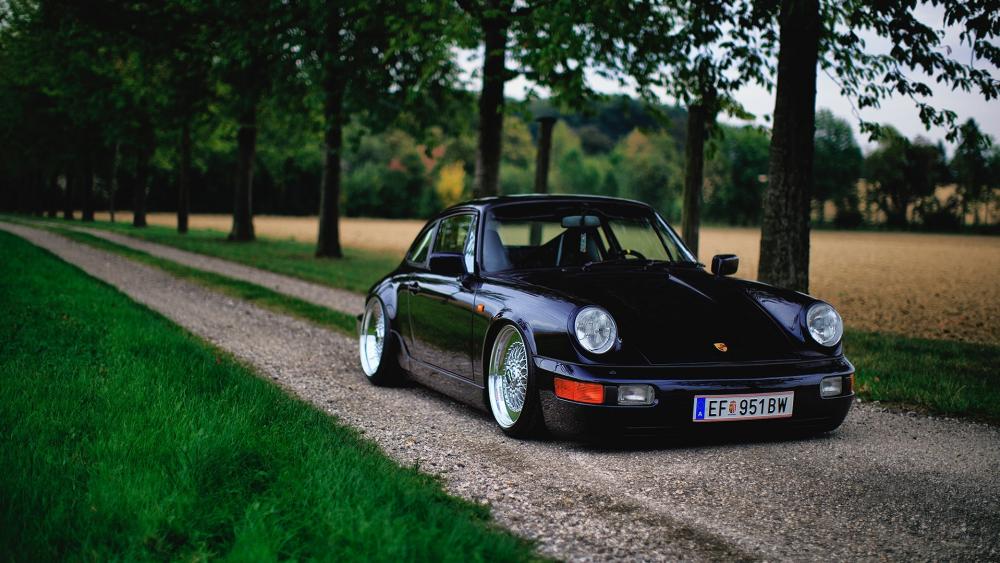 Sleek Black Porsche Excellence on a Tranquil Path wallpaper