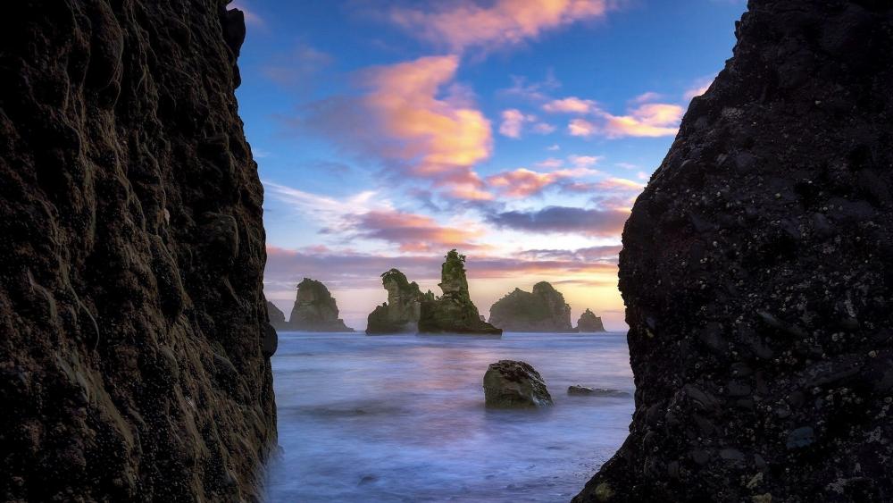 Serene Coastal Sunset Amidst Dramatic Rocks wallpaper