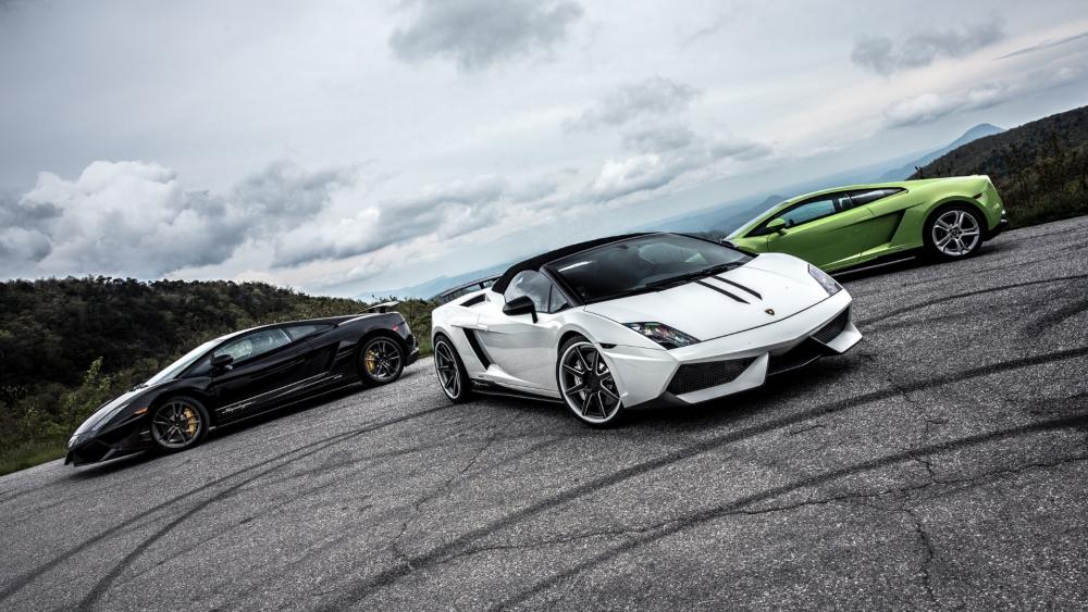 Ultimate Sports Car Trio Displayed on Scenic Road wallpaper