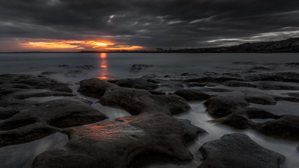 Dramatic Sunset Over Rocky Shoreline wallpaper