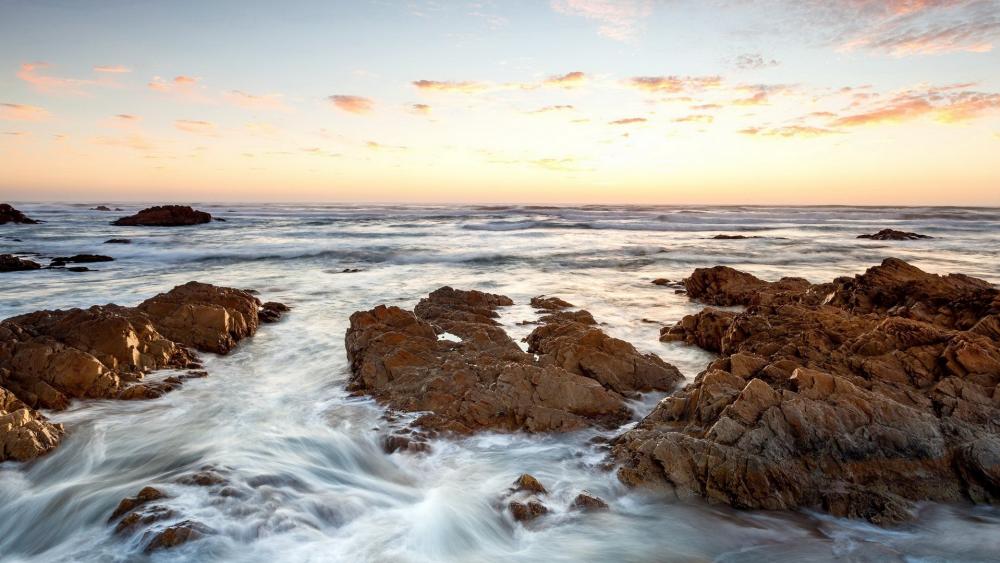 Serene Seaside Sunset Over Rocky Shoreline wallpaper