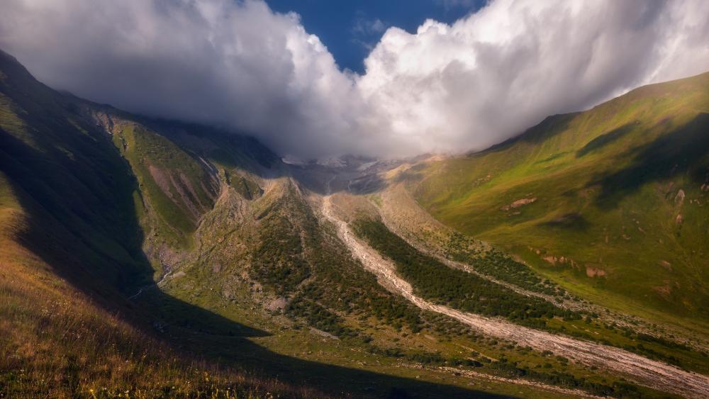 Majestic Mountain Valley Under Cloudy Sky wallpaper
