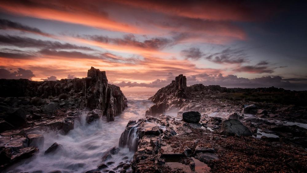 Dramatic Sunset Over Rocky Coastline Waves wallpaper