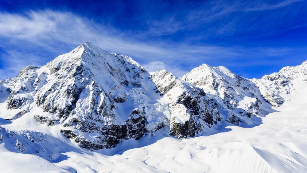 Majestic Snow-Capped Peaks Under Blue Sky wallpaper