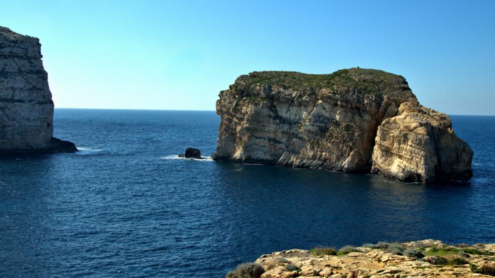 Breathtaking Coastal Rock Formation Under Clear Blue Skies wallpaper
