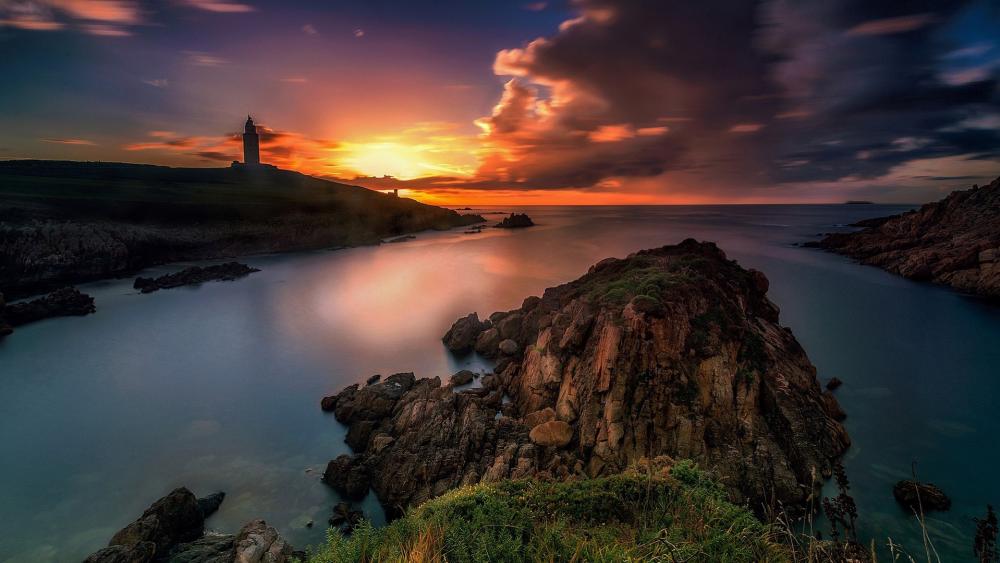 Serene Coastal Sunset Over Rocky Shoreline wallpaper