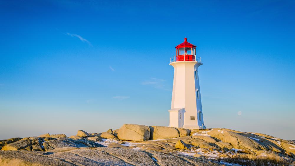 Lighthouse on Rocky Shoreline Under Clear Blue Sky wallpaper
