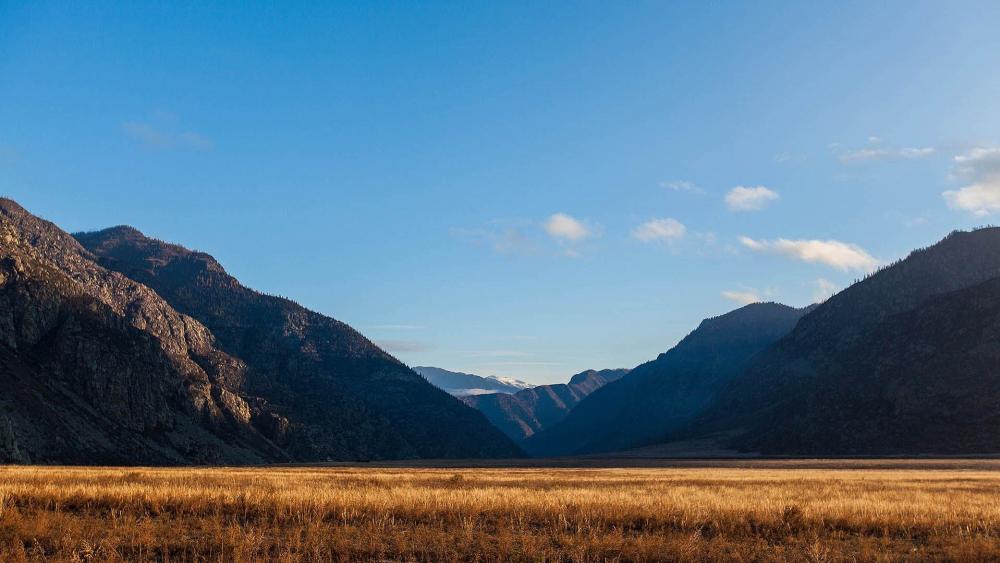 Serene Valley Surrounded by Majestic Mountains wallpaper