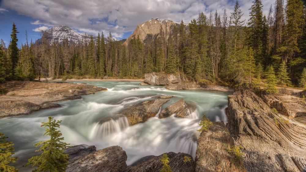 Serene River Flow Surrounded by Majestic Mountains wallpaper