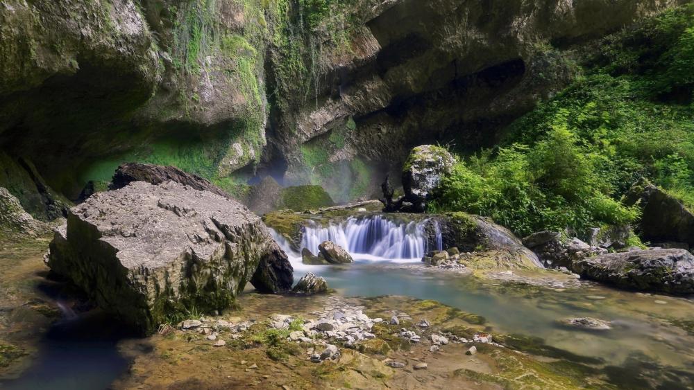 Serene Waterfall in a Lush Green Landscape wallpaper