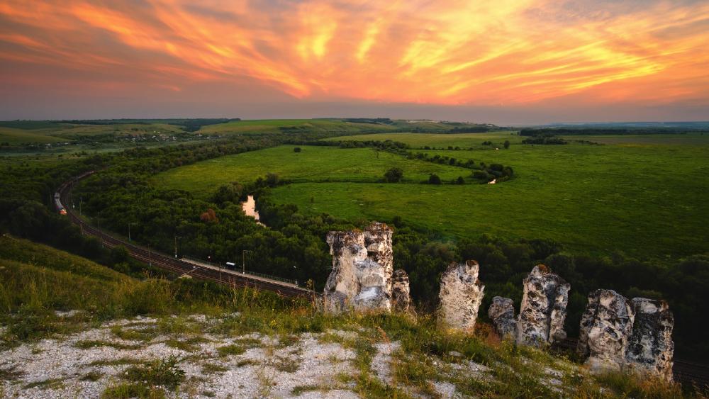 Serene Sunset Over Rolling Green Hills and Cliffs wallpaper