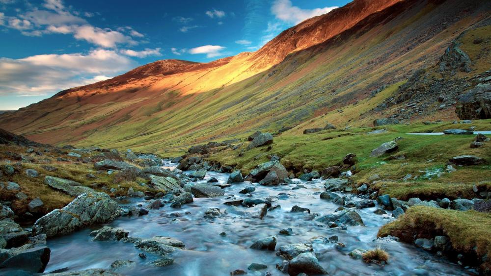 Serene Mountain Stream Amidst Majestic Peaks wallpaper