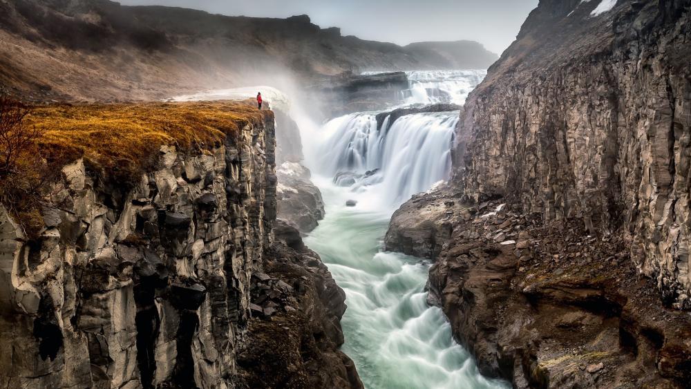 Majestic Waterfall and Rugged Cliffs in Nature's Embrace wallpaper