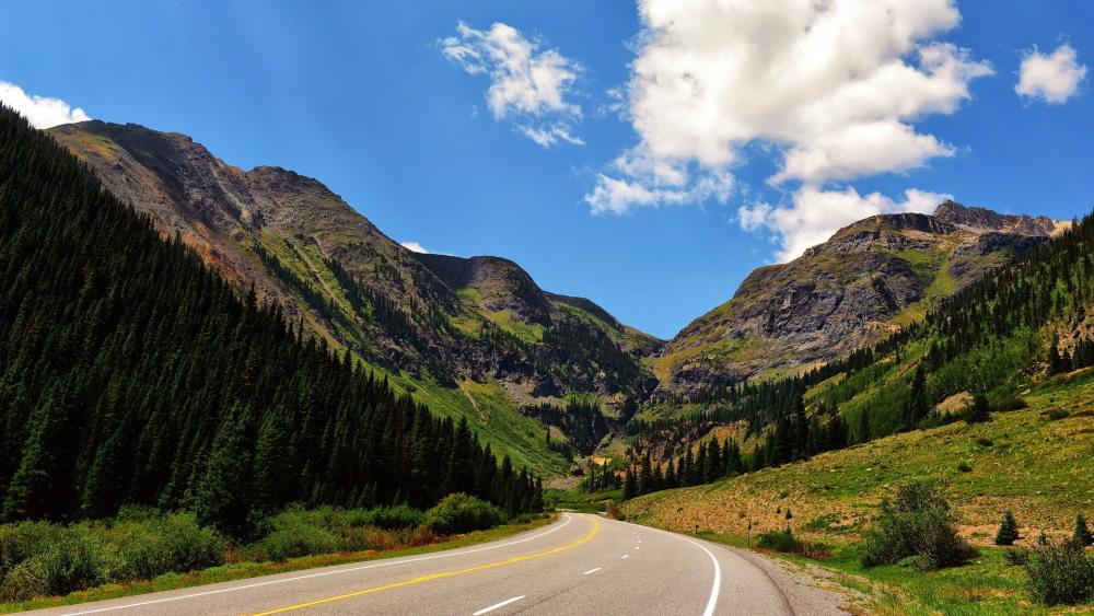 Scenic Mountain Road Under Blue Sky wallpaper