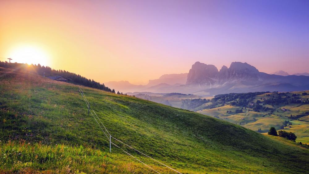 Serene Sunrise over Majestic Mountains and Green Hills wallpaper