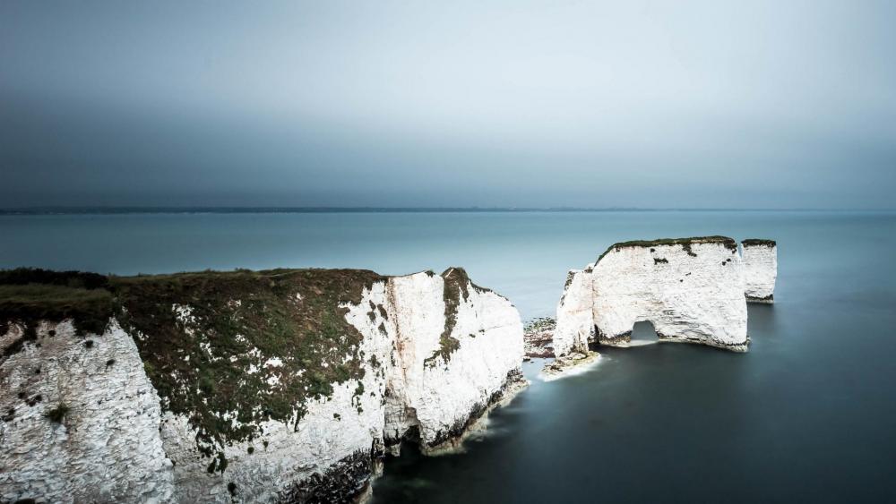 Majestic Coastal Cliffs Under Soft Gray Skies wallpaper