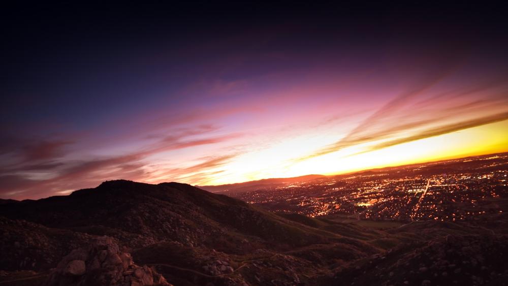 Captivating Sunset Over Hills and City Lights wallpaper