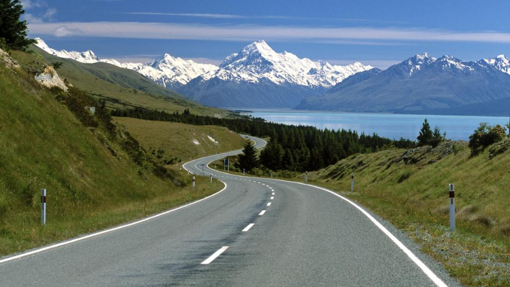 Scenic Road Leading to Majestic Mountains and Lake Waters wallpaper