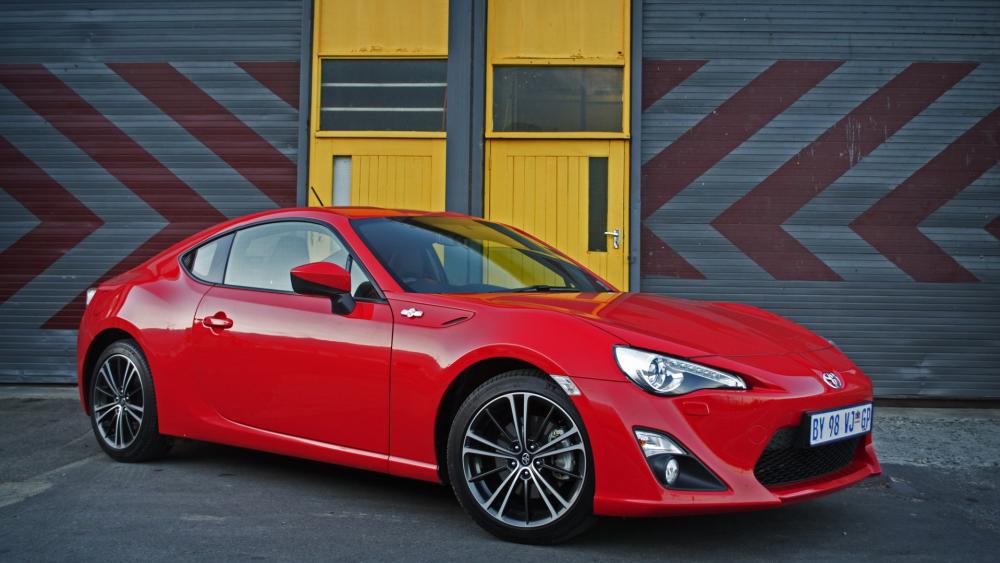 Sleek Red Sportscar Against Industrial Backdrop wallpaper