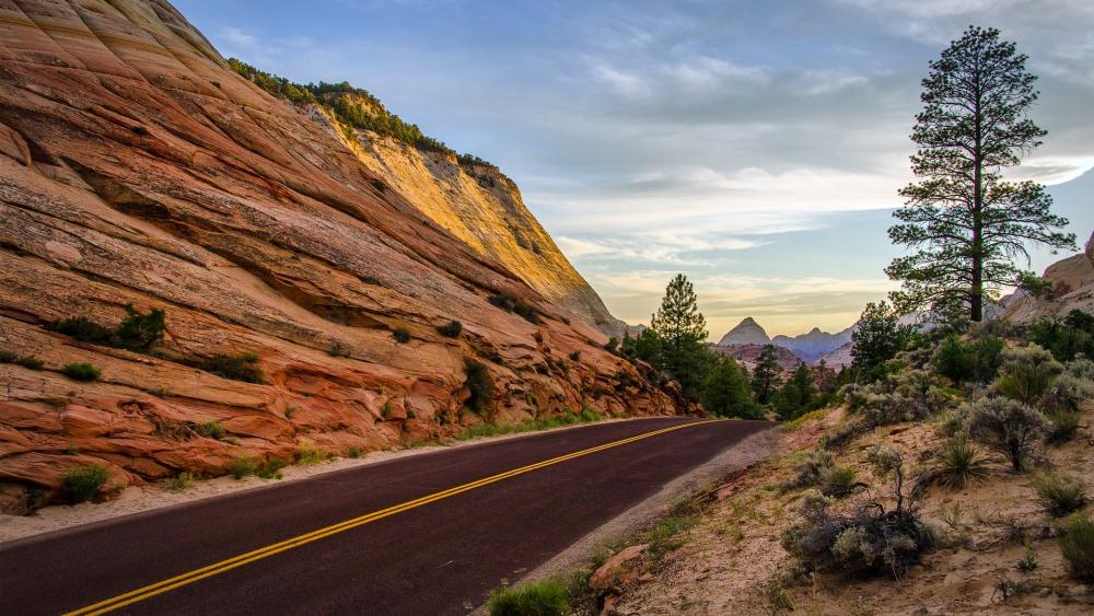 Stunning Desert Road Surrounded by Majestic Mountains wallpaper