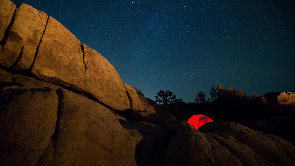 Starlit Night over Rocky Terrain with Tent Glow wallpaper