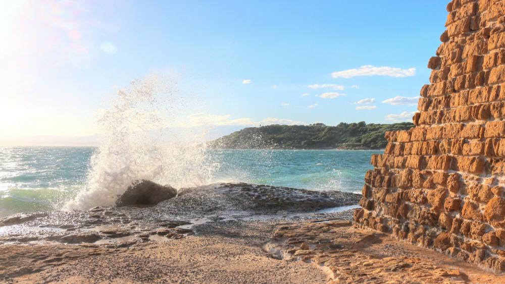 Serene Coastal Waves Lapping Against Ancient Rocks wallpaper