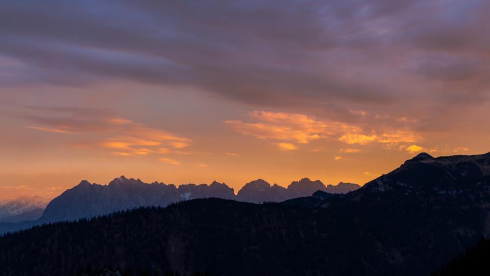 Majestic Mountain Sunset Over Rolling Hills wallpaper