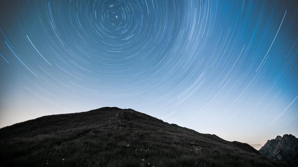 Swirling Star Trails Over Serene Mountain wallpaper