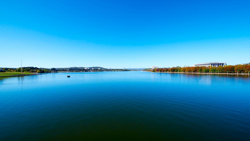 Serene Lakeside Landscape Under Bright Blue Sky wallpaper