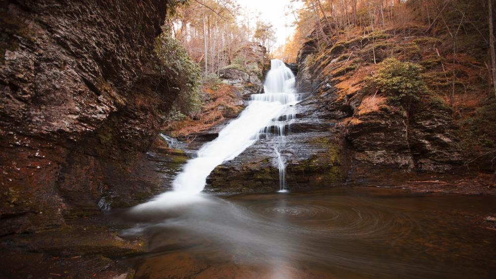 Majestic Waterfall in Serene Forest Setting wallpaper