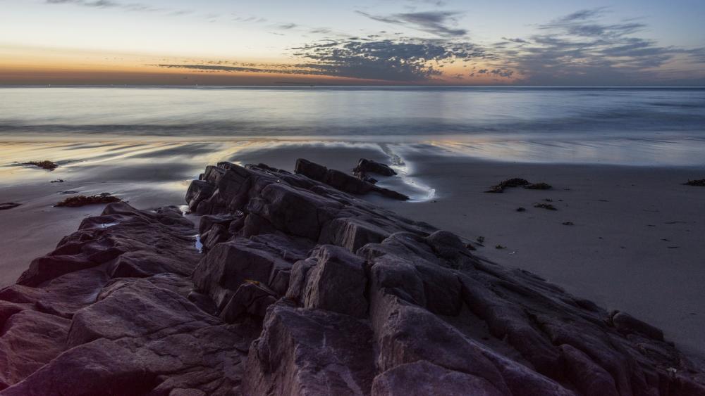 Serene Sunset Over Rocky Shoreline wallpaper