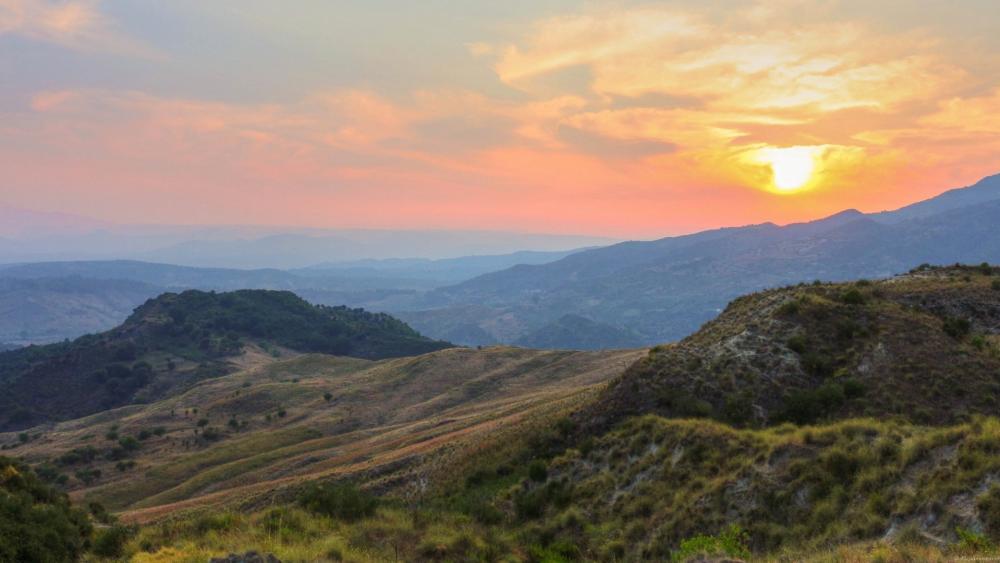 Serene Sunset Over Rolling Hills and Valleys wallpaper