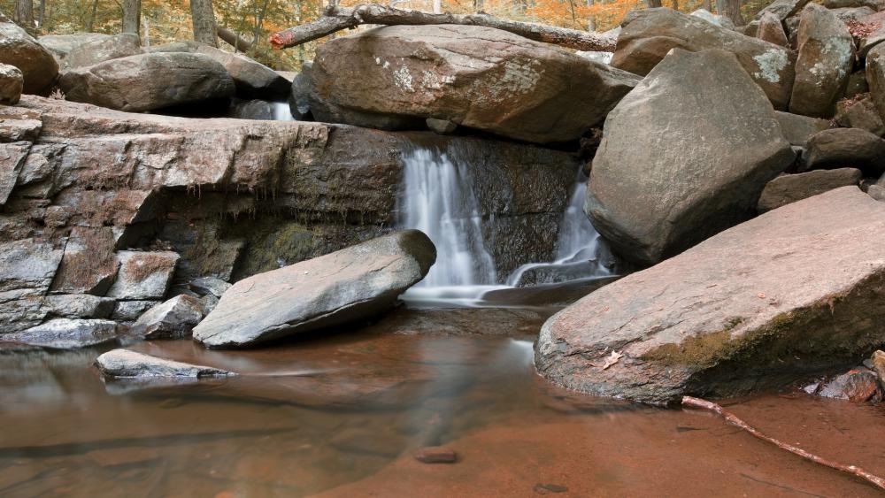 Serene Waterfall Amidst Rocky Landscape wallpaper