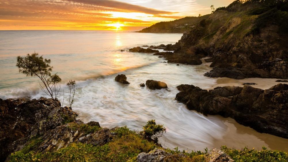 Serene Sunset Over Rocky Shoreline wallpaper