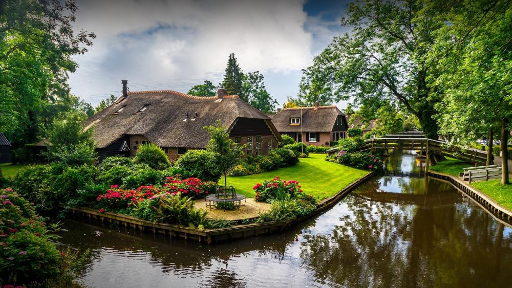 Charming Riverside Village with Lush Greenery and Tranquil Waters wallpaper