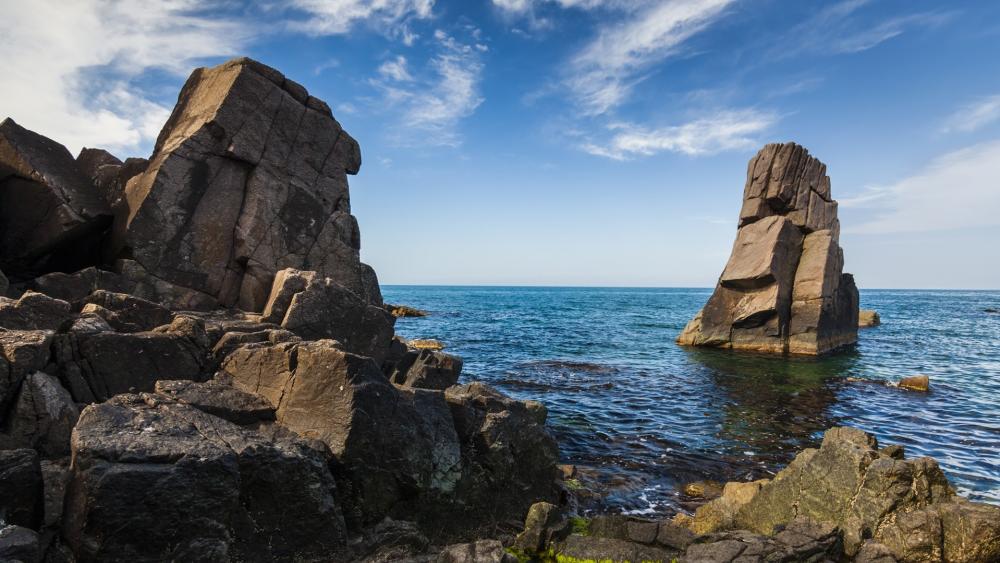 Majestic Rocky Coastline Under Blue Skies wallpaper
